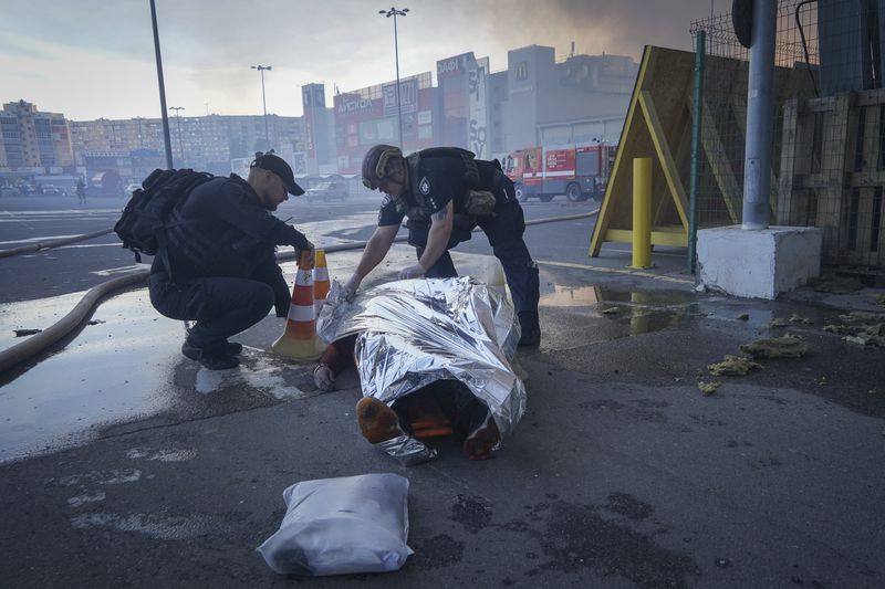 Police officers cover a dead body after two guided bombs hit a large construction supplies store in Kharkiv, Ukraine, Saturday, May 25, 2024. (AP Photo/Andrii Marienko)