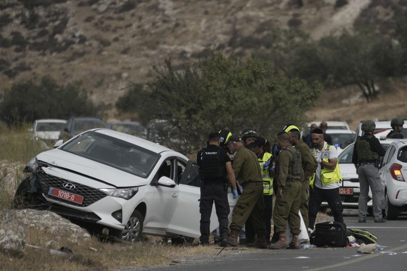 Israeli security forces and rescue services check the scene of a shooting attack in the West Bank city of Tarkumiya, Sunday, Sept. 1, 2024. Israeli authorities said Palestinian gunmen killed a few Israelis in a shooting attack in the occupied West Bank. Israel has been carrying out large-scale military raids in the territory in recent days. (AP Photo/Mahmoud Illean)