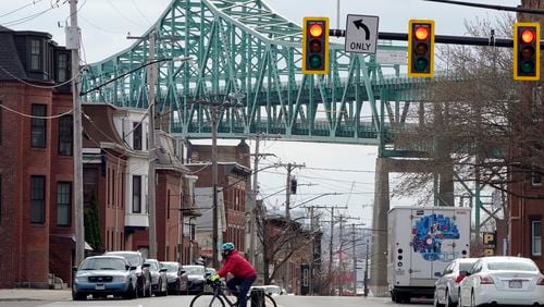 FILE - A cyclist rides along a street near the Tobin Memorial Bridge, background, in Chelsea, Mass., on Wednesday, March 31, 2021. After nearly 1,750 low-income people in the Boston suburb won a lottery to receive monthly stipends from the city from November 2020 to August 2021, researchers found that winners visited emergency departments significantly less than people who did not receive the monthly payments. (AP Photo/Steven Senne, File)