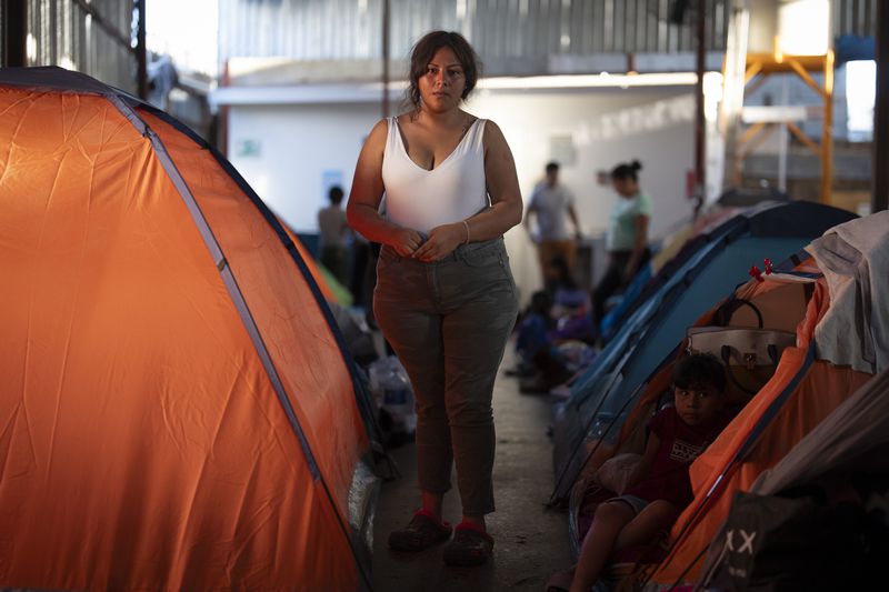 Maria, a migrant from southern Mexico, poses as others watch the presidential debate in a shelter for migrants waiting to apply for asylum, Thursday, June 27, 2024, in Tijuana, Mexico, as U.S. President Joe Biden and his Republican rival, Donald Trump, met for the first general election debate of the 2024 season. (AP Photo/Gregory Bull)