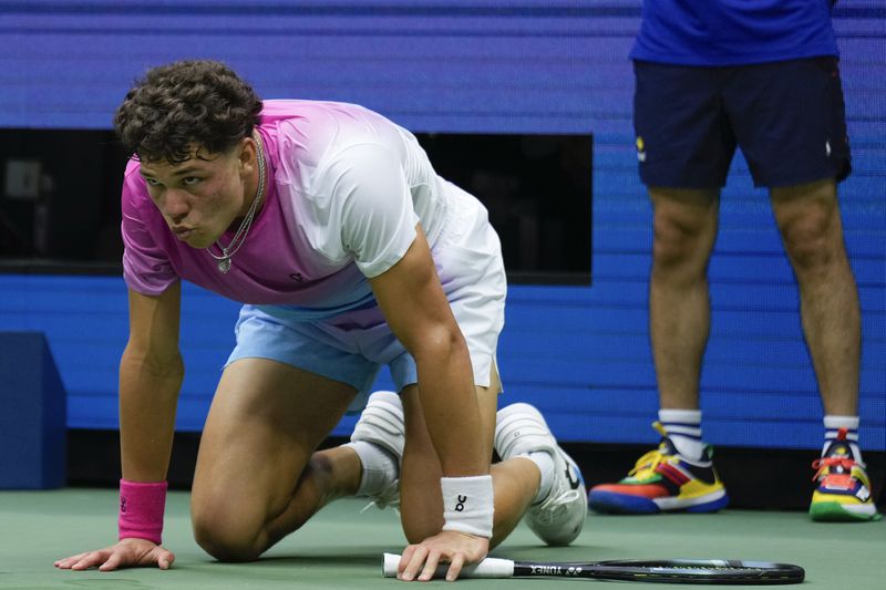 Ben Shelton, of the United States, gets up off the court after tripping on a shot to Frances Tiafoe, of the United States, during the third round of the U.S. Open tennis championships, Friday, Aug. 30, 2024, in New York. (AP Photo/Seth Wenig)