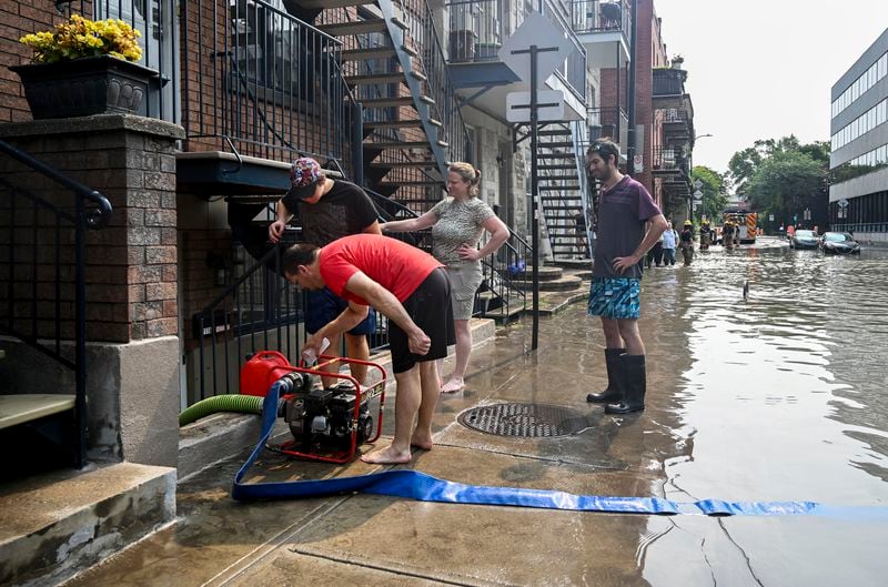 People use a pump to remove water from a basement apartment following a water main break on a street in Montreal, Friday, Aug. 16, 2024, causing flooding in several streets of the area. (Graham Hughes/The Canadian Press via AP)