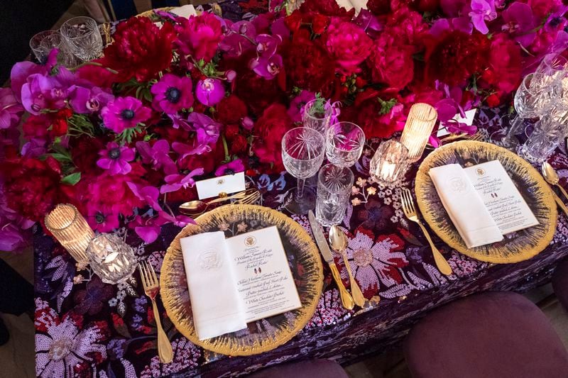 Sample place settings are seen atop a sequined table cloth with a colorful flower arrangement during a preview of the State Dinner with Kenya, Wednesday, May 22, 2024, at the White House in Washington. (AP Photo/Jacquelyn Martin)
