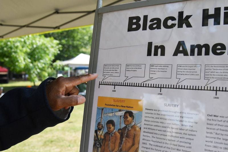 Lonnie Davis points at a “Black History in America” timeline at this tent at the 32nd Juneteenth Freedom Festival on Saturday, June 15, 2024, at Tattnall Square Park in Macon, Georgia. Davis does living history presentation on the Georgia African Brigade, three Black Union regiments that organized in Macon during the Civil War. (Photo Courtesy of Katie Tucker)