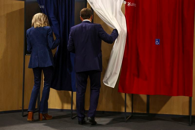 French President Emmanuel Macron and his wife Brigitte Macron enter a voting booth during the European election, Sunday, June 9, 2024 in Le Touquet-Paris-Plage, northern France. Polling stations opened across Europe on Sunday as voters from 20 countries cast ballots in elections that are expected to shift the European Union's parliament to the right and could reshape the future direction of the world's biggest trading bloc. (Hannah McKay/Pool via AP)