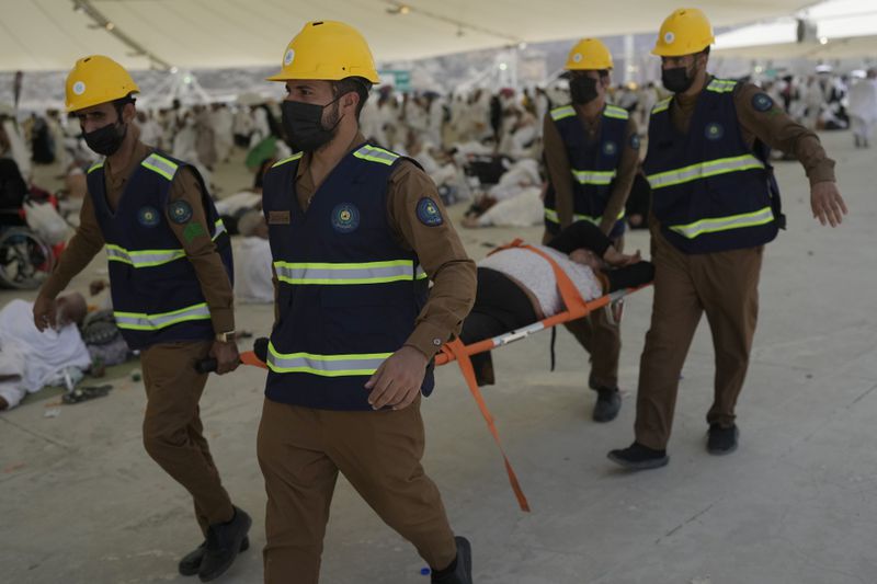 Paramedics carry a muslim pilgrim for a medical check after he fell down due to a heat stroke at pillars, in Mina, near the holy city of Mecca, Saudi Arabia, Sunday, June 16, 2024. Masses of pilgrims on Sunday embarked on a symbolic stoning of the devil in Saudi Arabia. The ritual marks the final days of the Hajj, or Islamic pilgrimage, and the start of the Eid al-Adha celebrations for Muslims around the world. (AP Photo/Rafiq Maqbool)