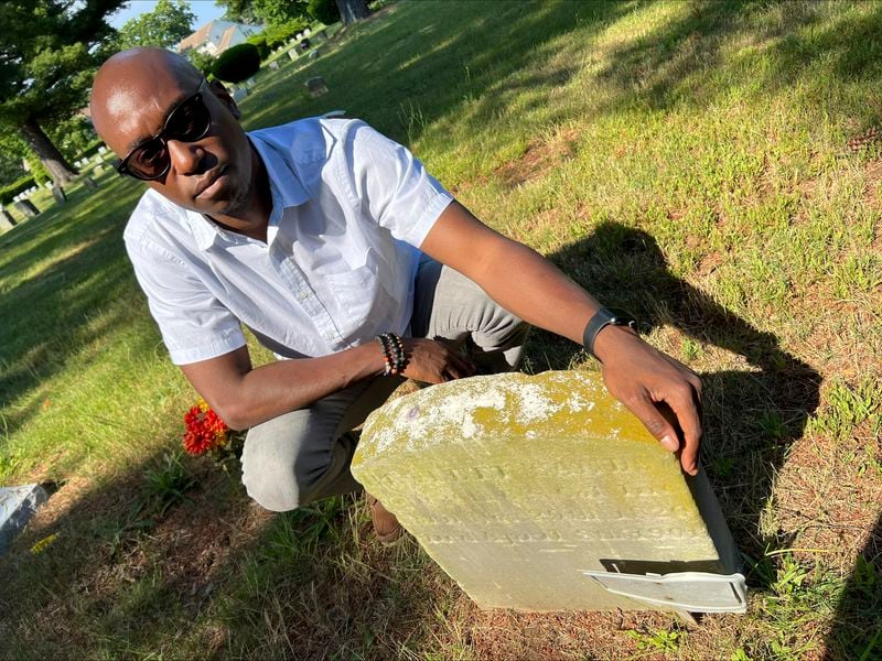 The Associated Press religion reporter Darren Sands poses by the gravestone of his great-great-great-great-grandfather and Civil War soldier Hewlett Sands in Westbury, N.Y., Monday, June 17, 2024. Hewlett Sands, born into slavery, served in the 26th United States Colored Infantry. He will be honored in a Juneteenth ceremony in Washington, D.C., along with about 200,000 other Black soldiers who fought to preserve the Union. (AP Photo/Lonnie Sands)