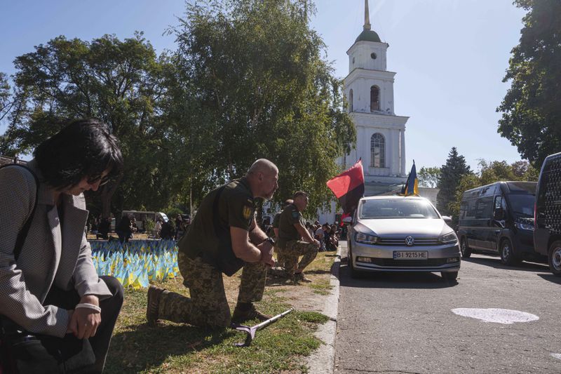 Ukrainian servicemen kneel during the funeral ceremony of six of their comrades who were killed in a Russian rocket attack at a Ukrainian military academy, in Poltava, Ukraine, Saturday Sept. 7, 2024. (AP Photo/Evgeniy Maloletka)