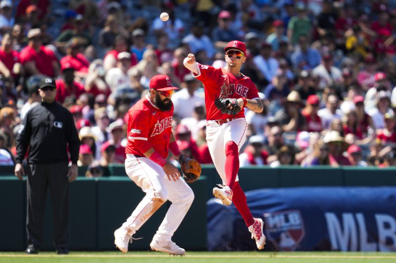 Los Angeles Angels shortstop Zach Neto (9) throws to first over third baseman Luis Guillorme during the eighth inning of a baseball game against the Cleveland Guardians in Anaheim, Calif., Sunday, May 26, 2024. (AP Photo/Ashley Landis)