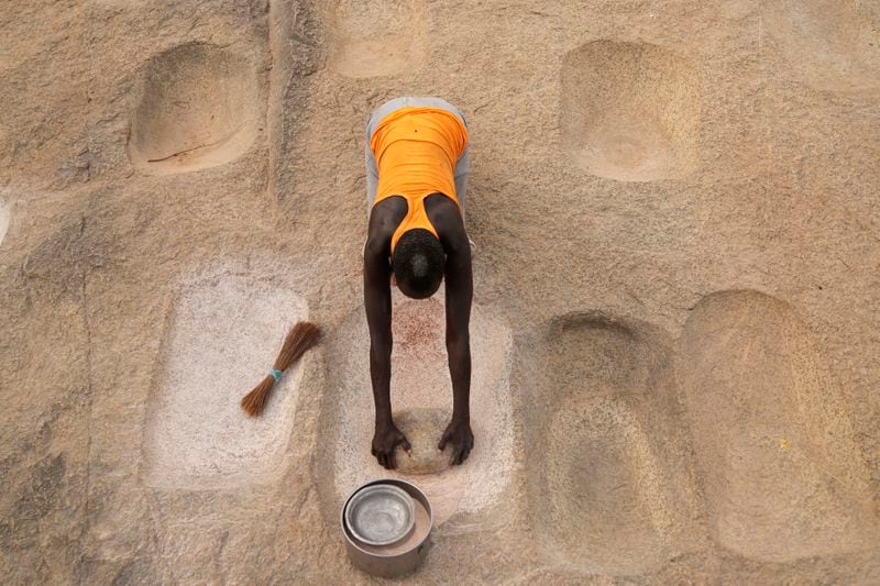 A woman works with flour in Lafon, South Sudan, Tuesday, June 18, 2024. African Parks has set up small hubs in several remote villages and is spreading messages of sustainable practices, such as not killing female or baby animals. (AP Photo/Brian Inganga)