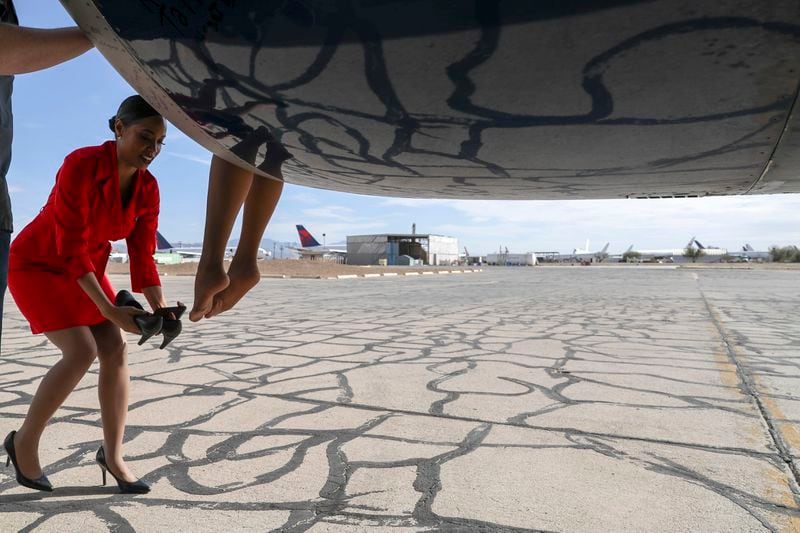 A Delta flight attendant helps her colleague dismount from the engine of the retired Delta "Queen of the Skies" 747 airplane at Pinal Airpark in Marana, Arizona, on Wednesday, Jan. 3, 2018.   