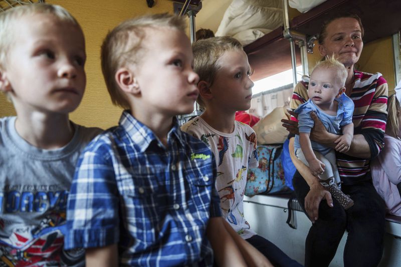 Iryna Belikova, 37, with her children, sit on an evacuation train in Pokrovsk, Donetsk region, Ukraine, Friday, Aug. 23, 2024.(AP Photo/Evgeniy Maloletka)