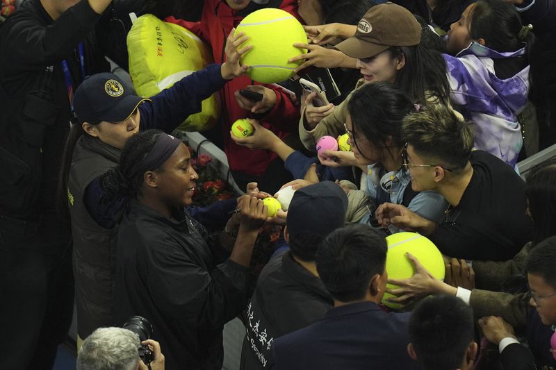 Coco Gauff of the United States signs autograph for fans after defeating Karolina Muchova of Czech Republic in the women's singles final match at the China Open tennis tournament at the National Tennis Center in Beijing, Sunday, Oct. 6, 2024. (AP Photo/Ng Han Guan)