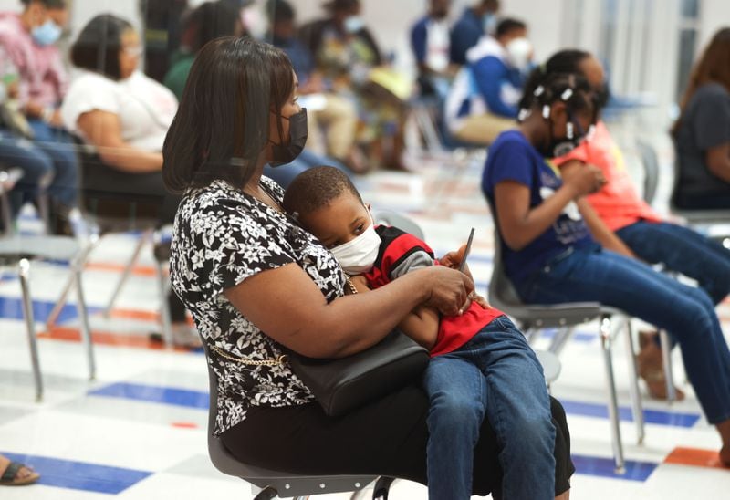 A woman, who asked not to be identified, holds a young child during a meeting on gun violence and school safety in Clayton County Schools at North Clayton Middle School on Tuesday, May 3, 2022, in College Park, Ga. Branden Camp/For the Atlanta Journal-Constitution