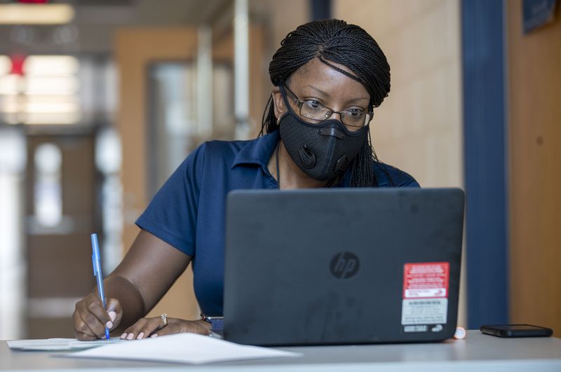 Mundy's Mill High School assistant principal Sequena Scott goes through paperwork for a parent who is looking to borrow a laptop for her child during a laptop distribution at the school in Jonesboro, Georgia on Sept. 1, 2020. (Alyssa Pointer / Alyssa.Pointer@ajc.com)