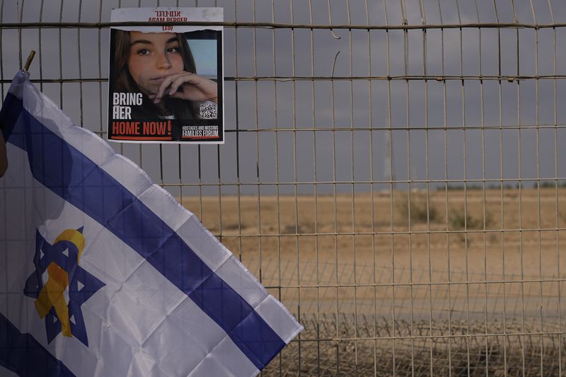 A photo of Agan Berger, who was kidnapped during Hamas militants attack on Oct. 7, hangs on a fence of the kibbutz Nirim as relatives and friends of the hostages held in the Gaza Strip take part in a protest calling for their release in southern Israel, Thursday, Aug. 29, 2024. (AP Photo/Tsafrir Abayov)