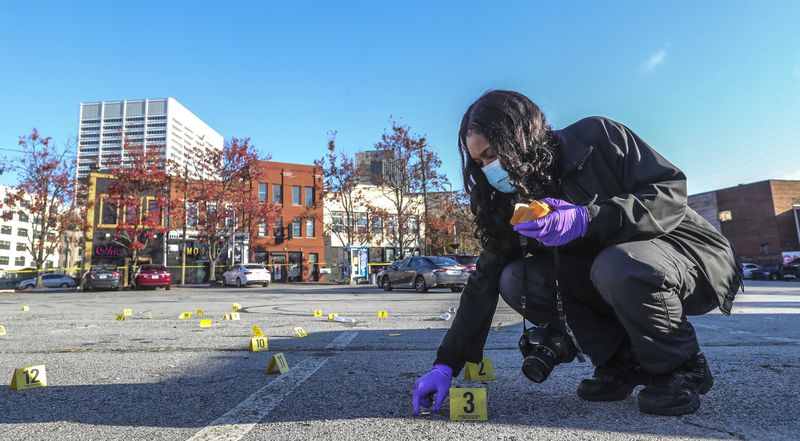 Atlanta Police Crime Technician K. Gallagher collects dozens of shell casings following a shooting outside a downtown Atlanta hookah lounge. (John Spink / John.Spink@ajc.com)

