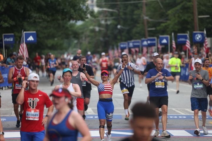Runners celebrate at the finish of the 55th running of the Atlanta Journal-Constitution Peachtree Road Race in Atlanta on Thursday, July 4, 2024.   (Jason Getz / AJC)