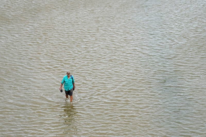 Joseph Canzanella walks through the storm surge from Tropical Storm Alberto to get to work Wednesday, June 19, 2024, in Surfside Beach, Texas. "This ain't the first time I've had to do this, and it won't be the last," he said. ( Jon Shapley/Houston Chronicle via AP)