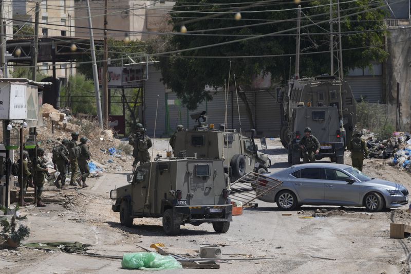 Members of Israeli forces patrol a street during a military operation in the West Bank refugee camp of Al-Faraa, Wednesday, Aug. 28, 2024. (AP Photo/Nasser Nasser)