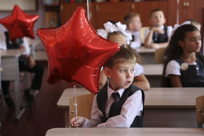 First graders sit in a classroom after a ceremony marking the start of classes at a school as part of the traditional opening of the school year known as "Day of Knowledge" in Makiivka, Russian-controlled Donetsk region, eastern Ukraine, on Monday, Sept. 2, 2024. (AP Photo/Alexei Alexandrov)