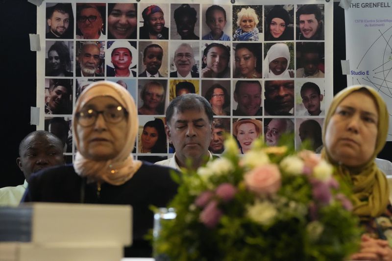 Relatives of the deceased and people directly affected by the Grenfell Tower fire, sit in front oaf a photo montage of the those who died, as they react to the final report into the fire being released in London, Wednesday, Sept. 4, 2024. The report on the Grenfell Tower fire in which 72 people were killed in June 2017, says decades of failure by government and industry made the high-rise a "death trap". (AP Photo/Frank Augstein)