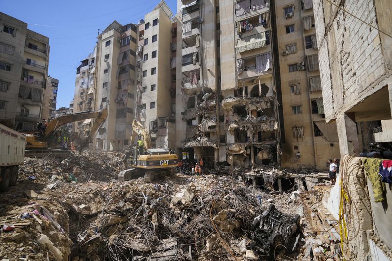 Emergency workers use excavators to clear the rubble at the site of Friday's Israeli strike in Beirut's southern suburbs, Lebanon, Monday, Sept. 23, 2024. (AP Photo/Hassan Ammar)