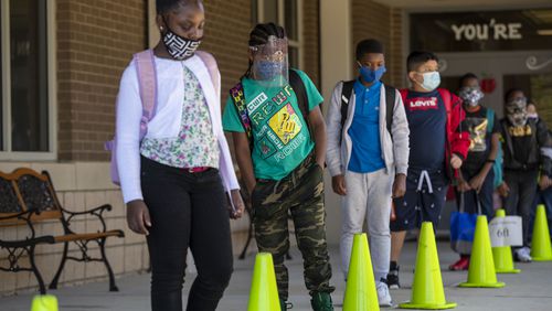 Clarkdale Elementary School wait at a social distance as they prepare to board their school busses after school in Austell on Oct. 5, 2020. This week, schools districts in Cobb and Gwinnett Counties plan to reopen schools amid a coronavirus  surge in Georgia. Masks are option in Cobb schools, while required in Gwinnett schools. (AJC file photo)