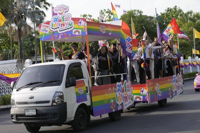 Participants wave flags celebrating equality in marriage at government house in Bangkok, Thailand, Tuesday, June 18, 2024. Thailand's Senate voted overwhelmingly on Tuesday to approve a marriage equality bill, clearing the last legislative hurdle for the country to become the first in Southeast Asia to enact such a law. (AP Photo/Sakchai Lalit)