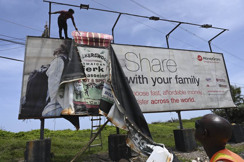 Workers dismantle an advertisement board to prevent damage from Hurricane Beryl in Kingston, Jamaica, Tuesday, July 2, 2024. (AP Photo/Collin Reid)