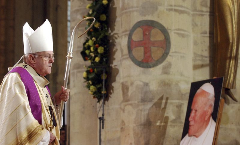 FILE -- Belgian Cardinal Godfried Danneels walks past a poster of Pope John Paul II, right, as he leads a memorial Mass for Pope John Paul II at the St. Michael church in Brussels, Sunday April 3, 2005. (AP Photo/Virginia Mayo, File)