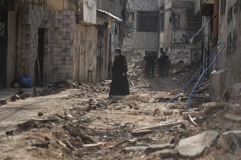 Palestinians walk on a damaged road following an Israeli military operation in the West Bank city of Jenin on Friday, Sept. 6, 2024. (AP Photo/Majdi Mohammed)