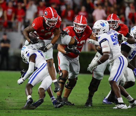 Georgia running back Kendall Milton gets extra yardage leaping over Kentucky defender Jordan Lovett for a 7-yard gain during the third quarter in a NCAA college football game on Saturday, Oct. 7, 2023, in Athens.  Curtis Compton for the Atlanta Journal Constitution