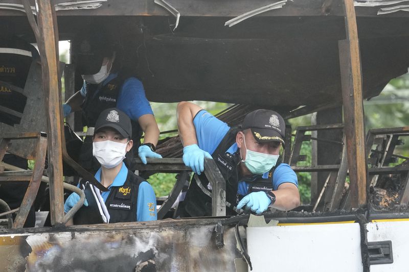 Officers of a police forensics team inspect a bus that caught fire, carrying young students with their teachers, in suburban Bangkok, Tuesday, Oct. 1, 2024. (AP Photo/Sakchai Lalit)