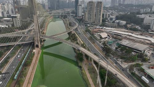 The Pinheiros River is green in Sao Paulo, Brazil, Tuesday, Sept. 10, 2024. The state's environmental authority attributes the river's new green hue to an algae bloom, the result of severe drought that has significantly lowered water levels. (AP Photo/Andre Penner)