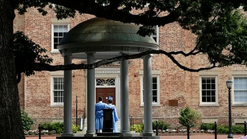 FILE - Graduates of the University of North Carolina take pictures at the Old Well on campus in Chapel Hill, N.C., June 30, 2020. (AP Photo/Gerry Broome, File)