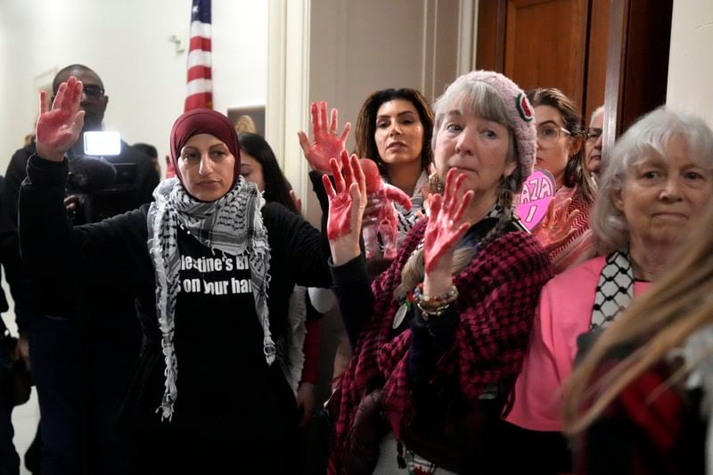 FILE - Activists with the group CodePink stand with red painted hands outside the office of House Minority Leader Hakeem Jeffries, D-N.Y., as they advocate for Gaza on Capitol Hill, Feb. 15, 2024, in Washington. Democratic lawmakers in the House and Senate are wrestling with whether to attend Israeli Prime Minister Benjamin Netanyahu's address to Congress on July 24, 2024. Netanyahu's visit to Capitol Hill is also expected to draw significant protests. Several groups, including some Jewish advocacy organizations, have demonstrated at congressional hearings and sit-ins outside of lawmakers' offices. (AP Photo/Mark Schiefelbein, File)