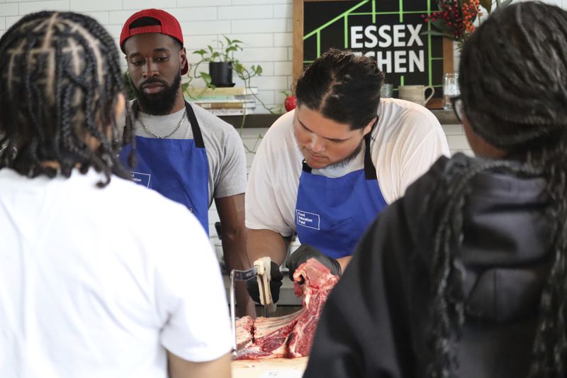 A George Westinghouse Career and Technical Education High School student cuts a side of beef at Essex Kitchen in New York, Tuesday, May 21, 2024. (AP Photo/James Pollard)