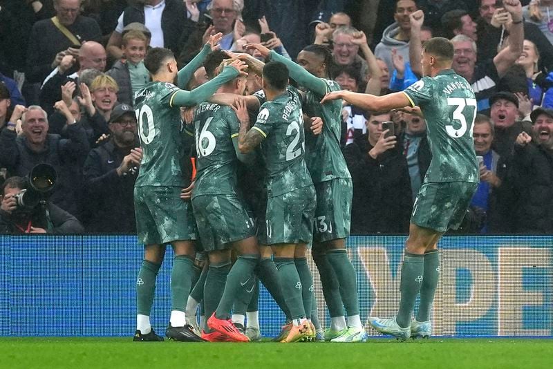 Tottenham Hotspur's Brennan Johnson, hidden, is surrounded by teammates as they celebrate after he scored their side's first goal of the game during the Premier League match at the American Express Stadium, Brighton, England, Sunday Oct. 6, 2024. (Gareth Fuller/PA via AP)