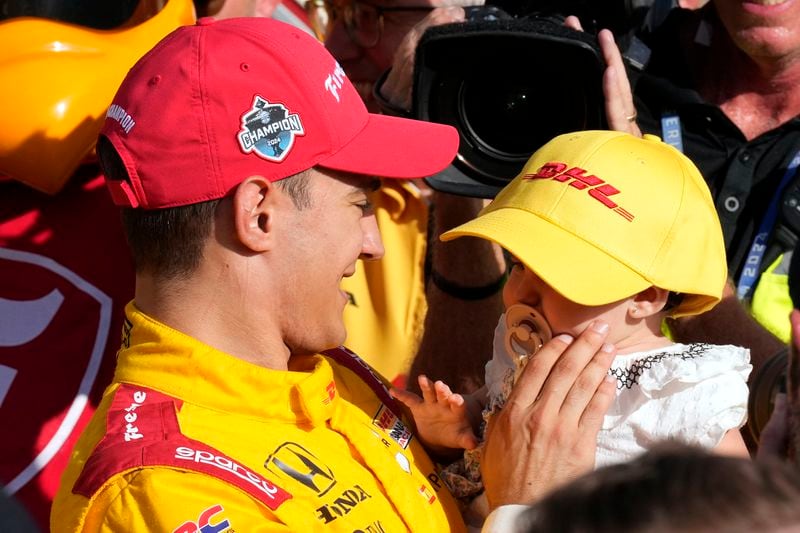 Alex Palou, left, holds his daughter after winning his third IndyCar championship in four years Sunday, Sept. 15, 2024, at Nashville Superspeedway in Lebanon, Tenn. (AP Photo/Mark Humphrey)