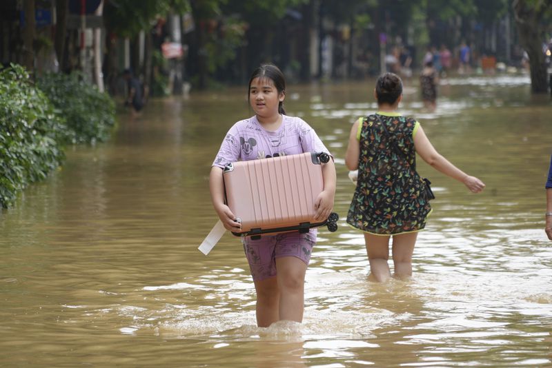 People carrying belongings wade in flooded street in the aftermath of Typhoon Yagi, in Hanoi, Vietnam on Thursday, Sept. 12, 2024. (AP Photo/Hau Dinh)