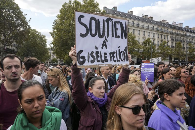 People take part in a gathering in support of 71-year-old Gisele Pelicot who was allegedly drugged by her ex-husband and raped by dozens of men while unconscious, Saturday, Sept. 14, 2024 in Paris. Placard reads, "support for Gisle Pelicot." (AP Photo/Michel Euler)