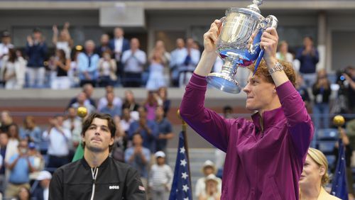 Jannik Sinner, of Italy, holds the championship trophy as Taylor Fritz, of the United States, looks on after sinner won the men's singles final of the U.S. Open tennis championships, Sunday, Sept. 8, 2024, in New York. (AP Photo/Kirsty Wigglesworth)