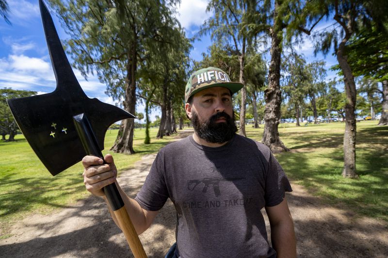 Andrew Roberts, director of the Hawaii Firearms Coalition, poses for a portrait with his halberd while talking to a Honolulu police officer at Kapiolani Park on Saturday, June 22, 2024, in Honolulu, Hawaii. (AP Photo/Mengshin Lin)