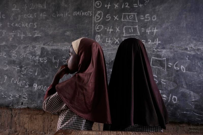 Students of Excellent Moral School attempt to answer a mathematics question on a blackboard inside a dimly lit classroom in Ibadan, Nigeria, Tuesday, May 28, 2024. Schools like Excellent Moral operate in darkness due to zero grid access, depriving students of essential tools like computers. (AP Photo/Sunday Alamba)