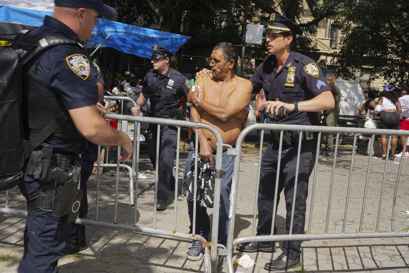 New York police officers escort a man injured during a shooting at the West Indian Parade, Monday, Sept. 2, 2024, in the Brooklyn borough of New York. (Nancy Siesel via AP)