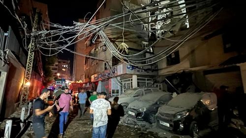 People gather near a destroyed building that was hit by an Israeli airstrike in the southern suburbs of Beirut, Lebanon, Tuesday, July 30, 2024. An Israeli airstrike hit Hezbollah's stronghold south of Beirut Tuesday evening causing damage, a Hezbollah official and the group's TV station said. (AP Photo/Hussein Malla)