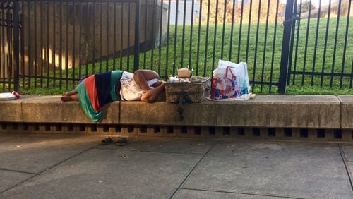 A woman sleeps on the ledge across from City Hall. Photo by Bill Torpy