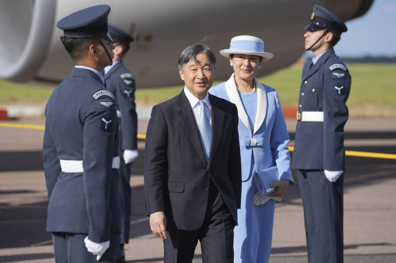 Emperor Naruhito and Empress Masako smile at the media walk through a guard of honour after arriving at Stansted Airport, England, Saturday, June 22, 2024, ahead of a state visit. The state visit begins Tuesday, when King Charles III and Queen Camilla will formally welcome the Emperor and Empress before taking a ceremonial carriage ride to Buckingham Palace. (AP Photo/Kin Cheung)