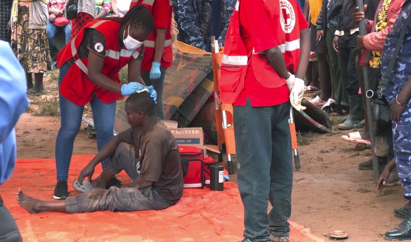 In this photo taken from video a man is helped by medical personal at a site of a collapsed landfill in Kampala, Uganda, Saturday, Aug. 10, 2024. At least 18 people were killed after a landfill collapsed late Friday in the Ugandan capital, according to the Red Cross. (AP video via AP)